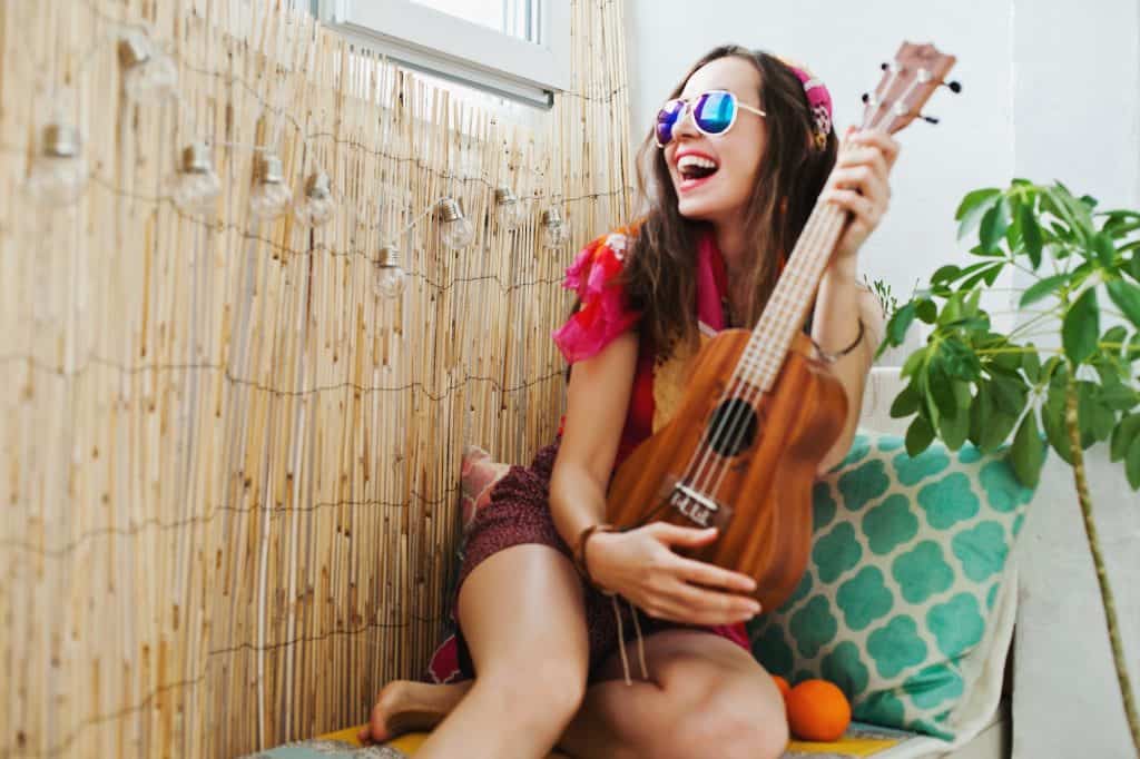 young woman with sunglasses with ukulele on terrace, smile,hippie, boho, free people, happy, relaxed